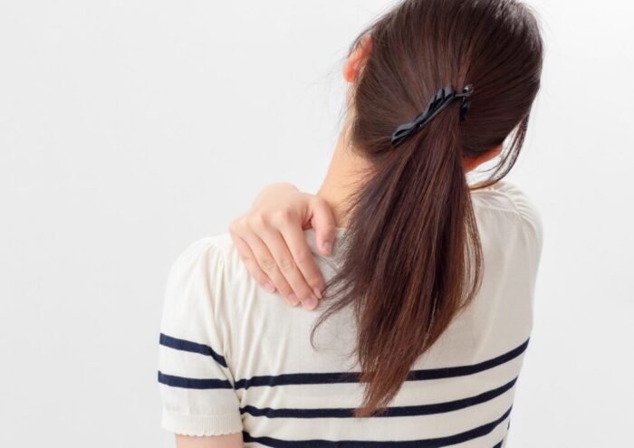 姿勢を意識しながら肩こりを感じている女性